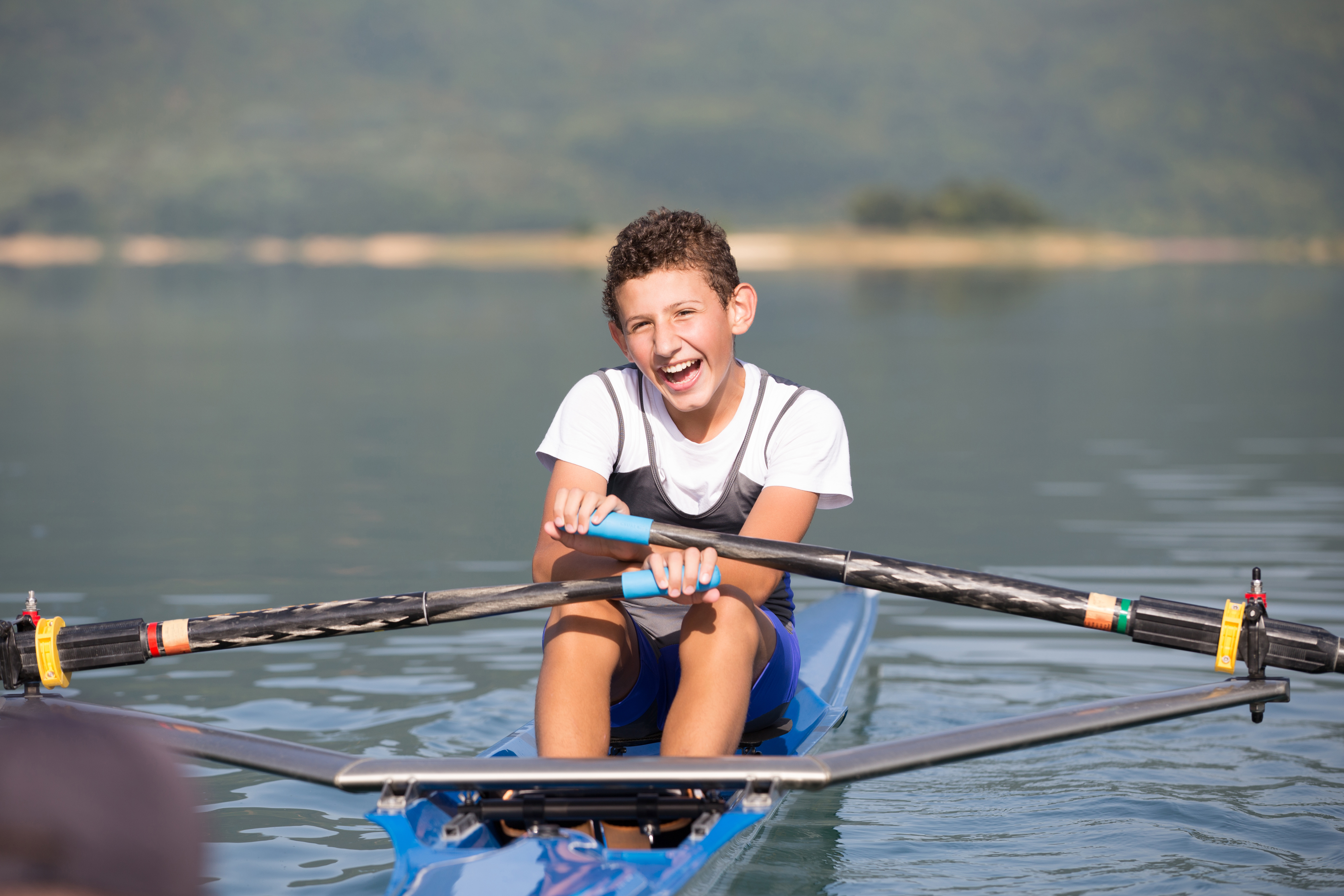 Young boy rowing on lake